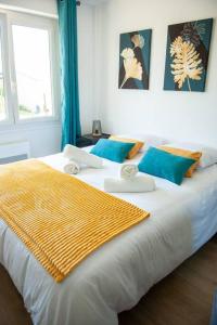 een groot wit bed met een gele deken erop bij Appartement Proche Gare Routière in Fougères