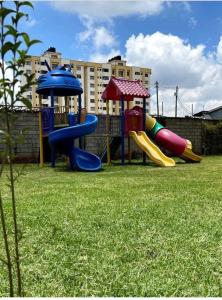 a playground with slides and an umbrella on the grass at Lux Suites Racecourse Gardens Studio Apartments in Nairobi