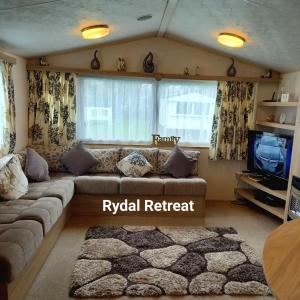 a living room with a couch and a tv at Rydal Retreat Lakeland Holiday Park in Flookburgh