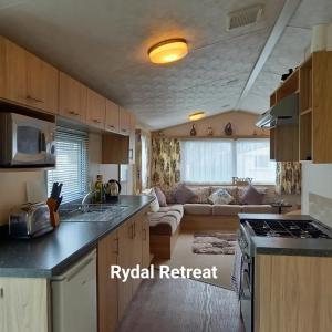 a kitchen and a living room with a couch at Rydal Retreat Lakeland Holiday Park in Flookburgh