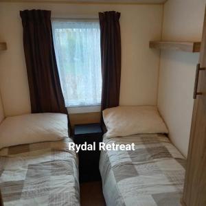 two beds in a small room with a window at Rydal Retreat Lakeland Holiday Park in Flookburgh
