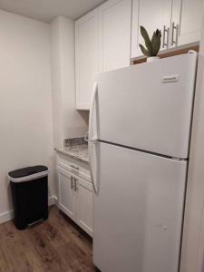 a white kitchen with a refrigerator and a trash can at Serene Studio Apt in Gadsden AL in Gadsden