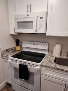 a white kitchen with a stove and a microwave at Serene Studio Apt in Gadsden AL in Gadsden