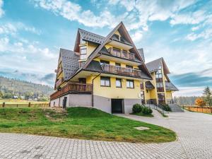 a large yellow house with a gambrel roof at VisitZakopane - Giewont View Apartment in Kościelisko