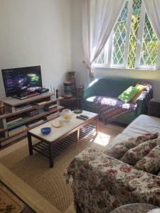 uma sala de estar com um sofá e uma televisão em Chalé Casa de Esther em Teresópolis