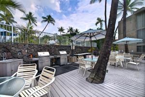 a deck with tables and chairs and a table with an umbrella at Alii Villas 309 in Kailua-Kona