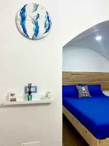 sypialnia z niebieskim łóżkiem i zegarem na ścianie w obiekcie Archi In Centro Apartment w mieście Vieste