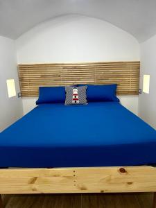 sypialnia z niebieskim łóżkiem z drewnianym zagłówkiem w obiekcie Archi In Centro Apartment w mieście Vieste