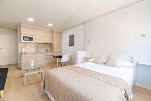 a bedroom with a large white bed and a kitchen at Loft Plaza España in Vigo