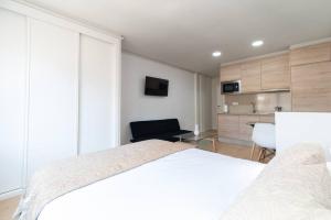 a bedroom with a white bed and a kitchen at Loft Plaza España in Vigo