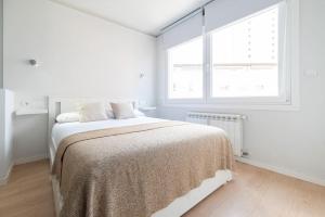 a white bedroom with a bed and a window at Loft Plaza España in Vigo