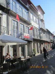 a street with tables and umbrellas in front of a building at Apartamentos Valdemar in Viana do Castelo