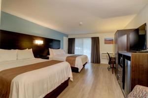 a hotel room with two beds and a flat screen tv at Quality Inn & Suites in Lincoln