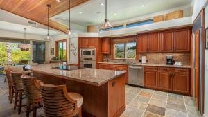 a kitchen with wooden cabinets and a large island with bar stools at Mauna Lani Villages 407 in Waikoloa