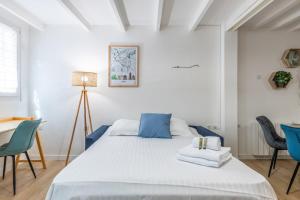 a white bedroom with a bed and chairs at Beautiful flat in the heart of Lyon - Welkeys in Lyon