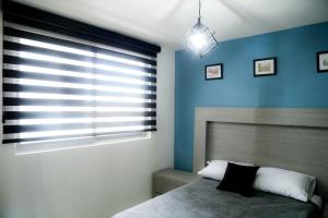 1 dormitorio con paredes azules, 1 cama y ventana en Comfort Flat In Guadalajara, en Guadalajara