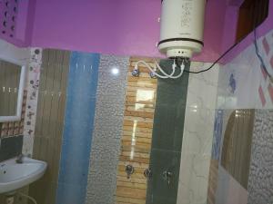 y baño con lavabo y ducha con luz. en Badrinath Jb Laxmi hotel, en Badrīnāth