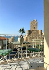 a table and chairs on a balcony with a clock tower at Iblu Rooms in Termoli