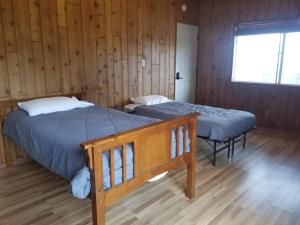 two beds in a room with wooden walls at 3BR Panoramic Lake View, Sequoia Forest, Kern County in Wofford Heights