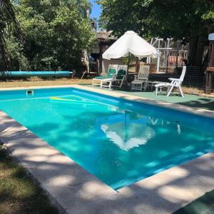 - une piscine bleue avec 2 chaises et un parasol dans l'établissement Beautiful Chalet Punta del Este, à Punta del Este