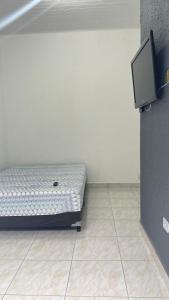 a small bed in a room with a tv at GL Pousada in Guarujá