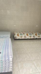 um quarto com duas camas e uma almofada no chão em GL Pousada no Guarujá