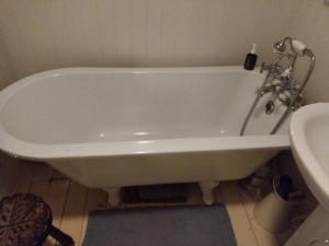 a white bath tub in a bathroom next to a sink at Detached Country Bungalow in Wroughton