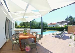 a patio with a table and chairs under a white umbrella at Villa Fjaka in Umag