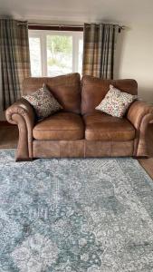 a brown leather couch in a living room with a window at Braffin @ Fellside Farm, Pennington, Ulverston in Pennington