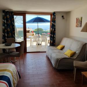 een woonkamer met een bank en een tafel met een paraplu bij Gites Pleine Nature Belledonne in Saint-Martin-dʼArdèche