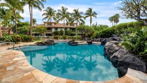 a swimming pool in front of a resort with palm trees at Waikoloa Beach Villas N32 in Waikoloa