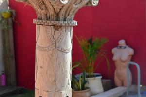 un pilar de madera con plantas y una pared roja en Quiet place 3 km from caesarea en Or ‘Aqiva