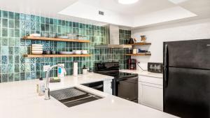 a kitchen with a sink and a black refrigerator at Casa de Emdeko 124 in Kailua-Kona