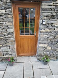a wooden door on a stone house with flowers at The Annexe in Ulverston
