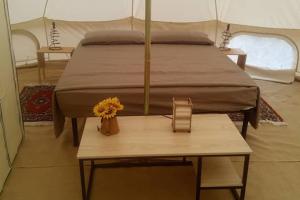 a bed in a tent with a table and flowers on it at Torre Lapillo Agricampeggio in Torre Lapillo