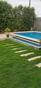 una piscina con césped y escaleras en un patio en Villa Bakr, en Naj‘ al Aḩwāl