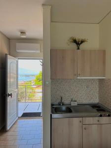 a kitchen with a sink and a view of the ocean at Bay Holiday Hotel & Spa in Karavómilos