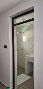 a bathroom with a glass door with a marble wall at Lala Inn Kikopey in Gilgil