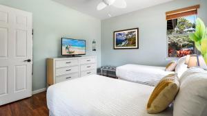 een slaapkamer met twee bedden en een flatscreen-tv bij Mauna Lani Fairways 1601 in Waikoloa