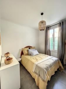 um quarto com uma cama e um lustre em Charmante maison de ville avec jardin, terrasse et terrain de pétanque em Fos-sur-Mer