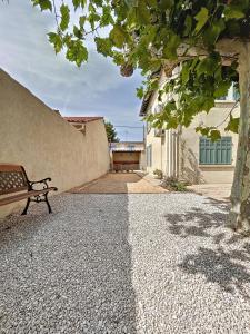 um banco de parque sentado ao lado de uma parede em Charmante maison de ville avec jardin, terrasse et terrain de pétanque em Fos-sur-Mer