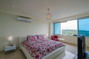 una camera da letto con un letto, una tv e una finestra di 19L Breathtaking Oceanview Playa Bonita Resort a ArraijÃ¡n