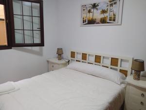 a bedroom with a white bed and two tables and two lamps at La Gaviota in Comillas
