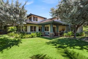 a house with a yard with green grass and trees at Kulalani at Mauna Lani 205 in Waikoloa