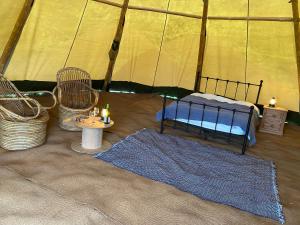 Zelt mit einem Bett, 2 Stühlen und einem Tisch in der Unterkunft Devon Tipi Camp And Glamp in Stoke Canon