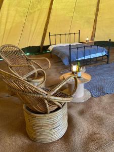 a wicker chair and a table in a tent at Devon Tipi Camp And Glamp in Stoke Canon