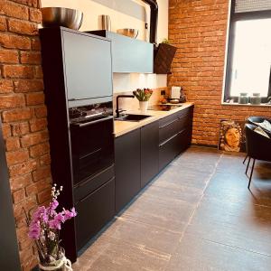 a kitchen with black cabinets and a brick wall at holidayAHRpartment in Bad Neuenahr-Ahrweiler