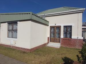 a white house with a green roof at Grassland 4 (Townhouse) in Bloemfontein