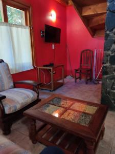 Una sala de estar con un sofá, una mesa y un televisor. en Casa de montaña rumel, en Villa La Angostura