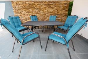 een groep stoelen en een tafel met blauwe stoelen bij Backyard Jacuzzi House in Oradea